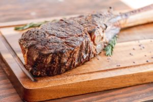 tomahawk bone-in steak cooked and displayed on a wooden cutting board