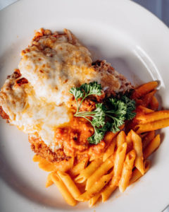veal parmesan paired with pasta with red sauce on a white plate